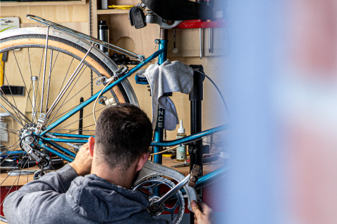 Un uomo ripara in autonomia una bicicletta d'epoca