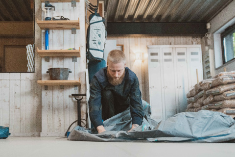 Un uomo ripara in autonomia il tessuto di una tenda Decathlon